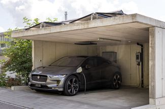 Ein silbernes Elektroauto lädt an einer Ladestation zuhause.