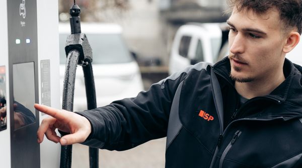 Ein Mitarbeiter der ISP Electro Solutions AG an einer öffentlichen Ladestation für Elektroautos.