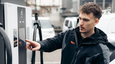 Ein Mitarbeiter der ISP Electro Solutions AG an einer öffentlichen Ladestation für Elektroautos.