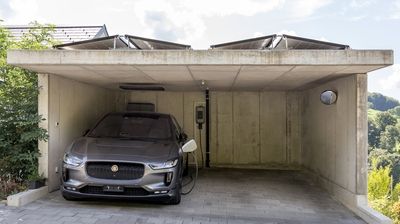Ein silbernes Elektroauto lädt an einer Ladestation zuhause.