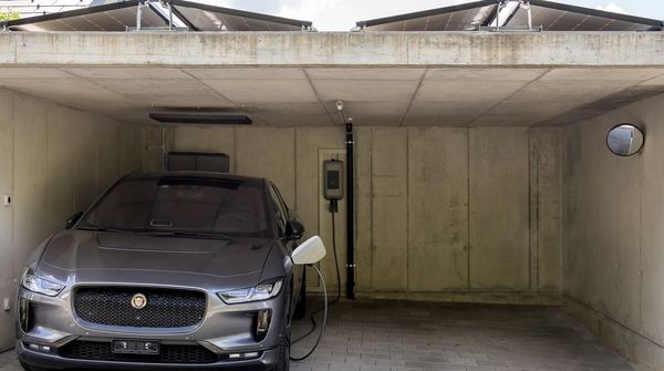 Ein silbernes Elektroauto lädt an einer Ladestation zuhause.