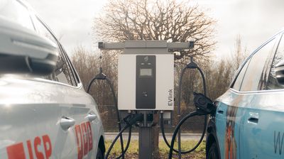 Zwei Elektroautos laden nebeneinander an einer öffentlichen Ladestation.