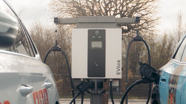 Zwei Elektroautos laden nebeneinander an einer öffentlichen Ladestation.